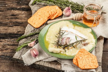Eritilmiş Rougette peyniri, taze biberiye ve sarımsaklı. Çıtır krakerler, tatlım. Füme kırmızı biberli nefis atıştırmalıklar. Ahşap arkaplan, kopyalama alanı