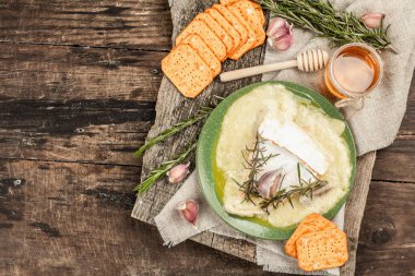 Eritilmiş Rougette peyniri, taze biberiye ve sarımsaklı. Çıtır krakerler, tatlım. Füme kırmızı biberli nefis atıştırmalıklar. Ahşap arkaplan, kapat
