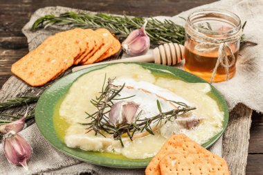 Eritilmiş Rougette peyniri, taze biberiye ve sarımsaklı. Çıtır krakerler, tatlım. Füme kırmızı biberli nefis atıştırmalıklar. Ahşap arkaplan, kapat