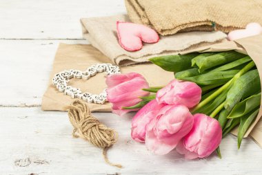 Bir buket taze pembe lale. Bahar çiçeklerini dikmek, uzay boşluklarını kopyalamak. Aletler, antika makas, el işi kağıt, yumuşak kalpler. Beyaz tahta arka plan