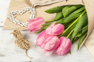 Bir buket taze pembe lale. Bahar çiçeği süslemesi yapıyorum. Aletler, antika makas, el işi kağıt, yumuşak kalpler. Beyaz tahta tahta arka plan, boşluğu kopyala