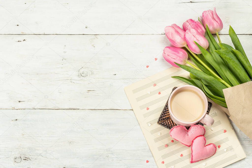 Romantic flat lay composition with a cup of coffee, soft felt hearts, and fresh tulips. Valentines or Mother's Day, Wedding, good morning concept. White wooden background, top view