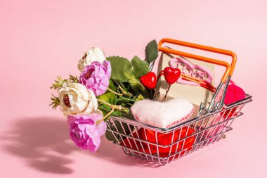 Pembe arka planda yalıtılmış bahar indirimi konsepti. İçinde bayram hediyeleri ve geleneksel Sevgililer Günü dekoru olan alışveriş sepeti. Modaya uygun sert ışık, karanlık gölge. Düz yatış, model, şablon