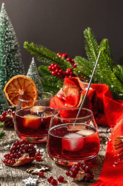 Meyve şurubu ve buzlu az alkollü kokteyl. Parlak maytaplar, geleneksel Noel dekorasyonu, yeni yıl kutlaması düzenlemesi. Samimi eşarp, yemyeşil dallar, ahşap arka plan.