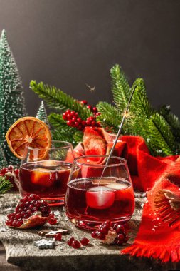 Meyve şurubu ve buzlu az alkollü kokteyl. Parlak maytaplar, geleneksel Noel dekorasyonu, yeni yıl kutlaması düzenlemesi. Samimi eşarp, yemyeşil dallar, ahşap arka plan.