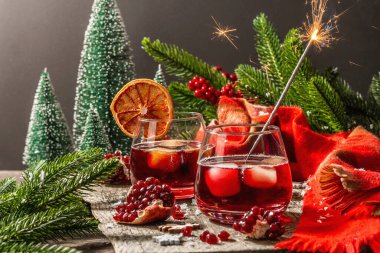 Meyve şurubu ve buzlu az alkollü kokteyl. Parlak maytaplar, geleneksel Noel dekorasyonu, yeni yıl kutlaması düzenlemesi. Samimi eşarp, yemyeşil dallar, ahşap arka plan.
