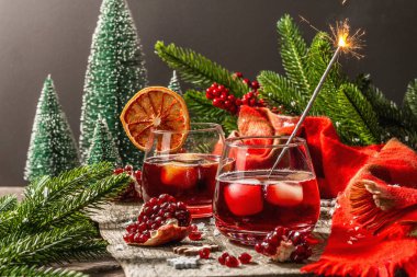 Meyve şurubu ve buzlu az alkollü kokteyl. Parlak maytaplar, geleneksel Noel dekorasyonu, yeni yıl kutlaması düzenlemesi. Samimi eşarp, yemyeşil dallar, ahşap arka plan.