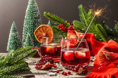 Meyve şurubu ve buzlu az alkollü kokteyl. Parlak maytaplar, geleneksel Noel dekorasyonu, yeni yıl kutlaması düzenlemesi. Samimi eşarp, yemyeşil dallar, ahşap arka plan.