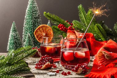 Meyve şurubu ve buzlu az alkollü kokteyl. Parlak maytaplar, geleneksel Noel dekorasyonu, yeni yıl kutlaması düzenlemesi. Samimi eşarp, yemyeşil dallar, ahşap arka plan.
