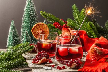 Meyve şurubu ve buzlu az alkollü kokteyl. Parlak maytaplar, geleneksel Noel dekorasyonu, yeni yıl kutlaması düzenlemesi. Samimi eşarp, yemyeşil dallar, ahşap arka plan.