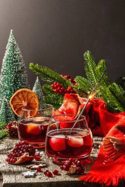Meyve şurubu ve buzlu az alkollü kokteyl. Parlak maytaplar, geleneksel Noel dekorasyonu, yeni yıl kutlaması düzenlemesi. Samimi eşarp, yemyeşil dallar, ahşap arka plan.