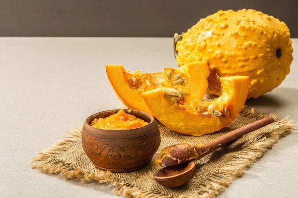 Autumn food cooking concept. Pumpkin puree, whole and cut pumpkins. Traditional fall symbol, stone background, close up