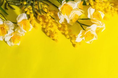 Geleneksel çiçeklerle bezenmiş bahar dairesi, parlak sarı arka plan. Paskalya kartı konsepti, modaya uygun sert ışık, koyu gölge, çerçeve, üst görünüm