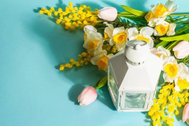 Beyaz fener ve geleneksel bahar çiçekleri mavi arka planda izole edilmiş. İnanılmaz bahar çiçekleri, Paskalya ya da Düğün konsepti, Sevgililer Günü veya Anneler Günü, boşluğu kopyala