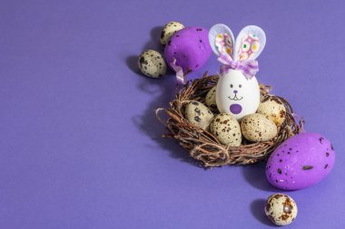 Hasır yuvasında şirin tavşan ve bıldırcın yumurtaları olan Paskalya bayramı kompozisyonu. Sert bir ışık, karanlık bir gölge, modaya uygun bir arka plan. Düz yatay tebrik kartı, satış, davet, kopyalama alanı