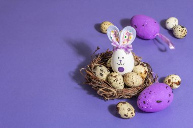 Hasır yuvasında şirin tavşan ve bıldırcın yumurtaları olan Paskalya bayramı kompozisyonu. Sert bir ışık, karanlık bir gölge, modaya uygun bir arka plan. Düz yatay tebrik kartı, satış, davet, kopyalama alanı