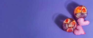 Greyfurtlu az alkollü kokteyl. Bardakta buzlu içecek servis edilir. St.Valentine 'ın sembolü. Sert ışık, koyu gölge, modaya uygun çok peri rengi arkaplan, afiş