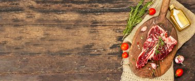 Taze biberiye, sarımsak ve baharatlı klasik biftek. Modern, sert bir ışık, karanlık bir gölge, modaya uygun bir duruş, ahşap arka plan, düz yatış. Ahşap arkaplan, rustik biçim, pankart biçimi