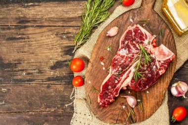 Taze biberiye, sarımsak ve baharatlı klasik biftek. Modern, sert bir ışık, karanlık bir gölge, modaya uygun bir duruş, ahşap arka plan, düz yatış. Ahşap arkaplan, köy tarzı, üst görünüm