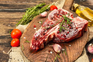 Taze biberiye, sarımsak ve baharatlı klasik biftek. Modern, sert bir ışık, karanlık bir gölge, modaya uygun bir duruş, ahşap arka plan, düz yatış. Ahşap arkaplan, rustik biçim, kopyalama alanı