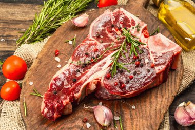 Taze biberiye, sarımsak ve baharatlı klasik biftek. Modern, sert bir ışık, karanlık bir gölge, modaya uygun bir duruş, ahşap arka plan, düz yatış. Ahşap arkaplan, köy tarzı, kapat