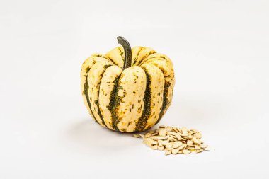 Olgun yeşil balkabağı ve tohumlar beyaz arka planda izole edilmiş. Cadılar Bayramı ya da Şükran Günü için geleneksel dekoratif öğe.