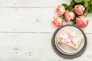 Beyaz ahşap arka planda romantik yemek masası. Sevgililer günü ya da anneler günü için aşk konsepti, düğün çatal bıçak takımı. Taze pembe güller, masa düzenleme, üst manzara.