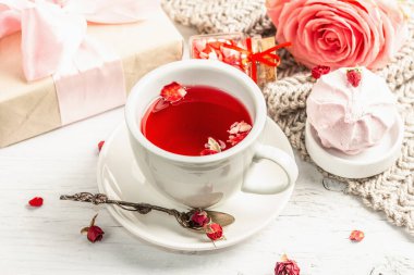Romantik çay kavramı. Paketlenmiş hediye, amber çayı, bir buket narin gül, şeker, şenlikli dekor. Sevgililer Günü konsepti, Kadınlar Günü 8 Mart, Düğün. Beyaz tahta arkaplanı, kapat