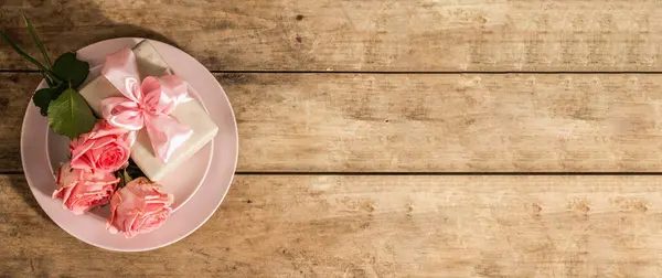 木製の素朴な背景にロマンチックなディナーテーブル バレンタインや母の日 結婚式のカトラリーのための愛の概念 繊細な新鮮なピンクのバラ ギフト ヴィンテージテーブル設定 バナー形式 — ストック写真