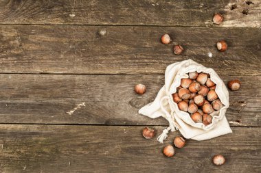 Kabuklu, olgun fındıklar. Çamaşır torbasında hasat, atıştırmalıklar için sağlıklı bir malzeme. Eski ahşap zemin, üst manzara