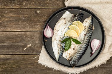 Baharatlı ve taze defne yapraklı marine edilmiş uskumru. Sağlıklı yiyecekler, yenmeye hazır, limonla servis ediliyor. Tahta kaplama arka plan, üst görünüm