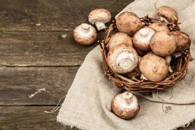 Hasır sepette taze kahverengi şampiyonlar. Vejetaryen yemeği pişirmek için ham malzemeler. Eski ahşap arkaplan, rustik biçim, kopyalama alanı