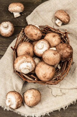 Hasır sepette taze kahverengi şampiyonlar. Vejetaryen yemeği pişirmek için ham malzemeler. Eski ahşap zemin, kırsal tarz, üst görünüm