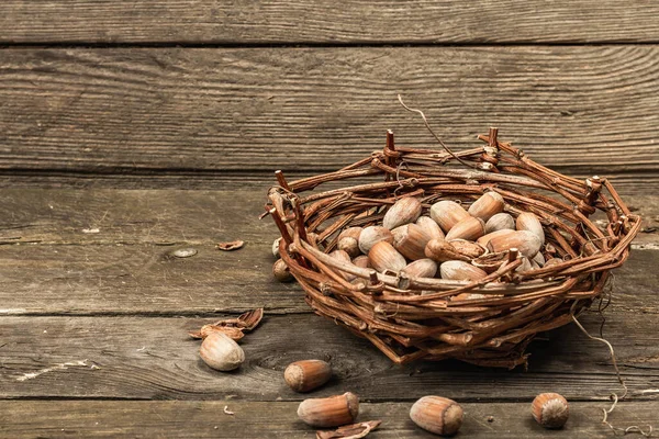 殻にヘーゼルナッツを熟す スナックのための健康的な成分であるウィッカーバスケットに収穫します 古い木の背景 コピースペース — ストック写真