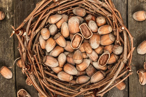 殻にヘーゼルナッツを熟す スナックのための健康的な成分であるウィッカーバスケットに収穫します 古い木の背景 トップビュー — ストック写真