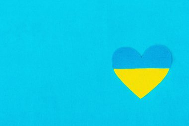 Ukrayna bayrağı renginde bir kalp. Savaş konseptini durdurun. Mavi arka plandaki kalp. Düz yatak, metin, model, şablon, üst görünüm için bir yer