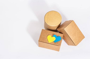 Ukrayna 'ya savaşta yardım etme kavramı. Beyaz arka planda izole edilmiş Ukrayna bayrağı renginde kalpleri olan kutular. Modern sert ışık, karanlık gölge