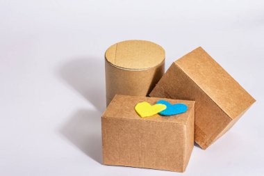 Ukrayna 'ya savaşta yardım etme kavramı. Beyaz arka planda izole edilmiş Ukrayna bayrağı renginde kalpleri olan kutular. Modern sert ışık, karanlık gölge