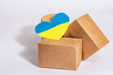 Ukrayna 'ya savaşta yardım etme kavramı. Beyaz arka planda izole edilmiş Ukrayna bayrağı renginde kalpleri olan kutular. Modern sert ışık, karanlık gölge