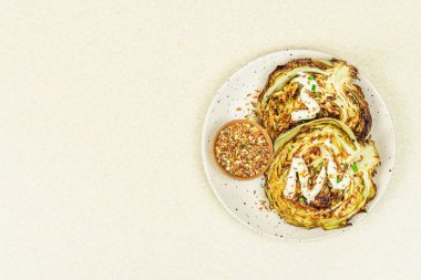 Ev yapımı vejetaryen lahana bifteği, baharat ve sos. Sağlıklı yiyecekler servis tabağında yemeye hazır. Taş beton zemin, üst görünüm