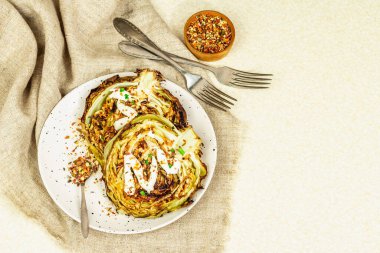 Ev yapımı vejetaryen lahana bifteği, baharat ve sos. Sağlıklı yiyecekler servis tabağında yemeye hazır, çatal bıçak takımı. Taş beton zemin, üst görünüm