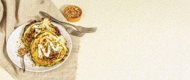 Ev yapımı vejetaryen lahana bifteği, baharat ve sos. Sağlıklı yiyecekler servis tabağında yemeye hazır, çatal bıçak takımı. Taş beton arkaplan, pankart biçimi