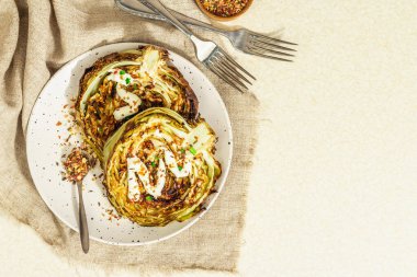 Ev yapımı vejetaryen lahana bifteği, baharat ve sos. Sağlıklı yiyecekler servis tabağında yemeye hazır, çatal bıçak takımı. Taş beton zemin, üst görünüm