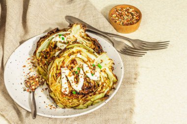 Ev yapımı vejetaryen lahana bifteği, baharat ve sos. Sağlıklı yiyecekler servis tabağında yemeye hazır, çatal bıçak takımı. Taş beton arka plan, kapat