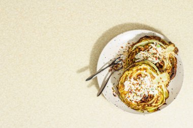 Ev yapımı vejetaryen lahana bifteği, baharat ve sos. Sağlıklı yiyecekler servis tabağında yemeye hazır, çatal bıçak takımı. Taş beton zemin, üst görünüm