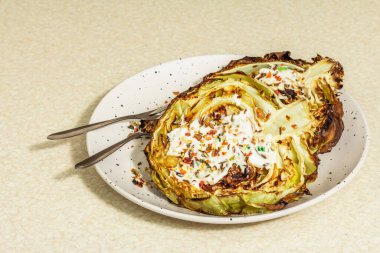 Ev yapımı vejetaryen lahana bifteği, baharat ve sos. Sağlıklı yiyecekler servis tabağında yemeye hazır, çatal bıçak takımı. Taş beton arka plan, kapat