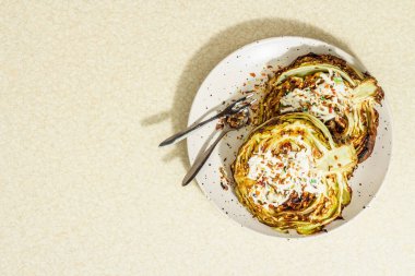 Ev yapımı vejetaryen lahana bifteği, baharat ve sos. Sağlıklı yiyecekler servis tabağında yemeye hazır, çatal bıçak takımı. Taş beton zemin, üst görünüm