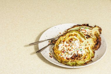 Ev yapımı vejetaryen lahana bifteği, baharat ve sos. Sağlıklı yiyecekler servis tabağında yemeye hazır, çatal bıçak takımı. Taş beton arkaplan, kopyalama alanı