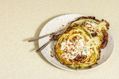 Ev yapımı vejetaryen lahana bifteği, baharat ve sos. Sağlıklı yiyecekler servis tabağında yemeye hazır, çatal bıçak takımı. Taş beton arkaplan, kopyalama alanı