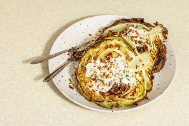 Ev yapımı vejetaryen lahana bifteği, baharat ve sos. Sağlıklı yiyecekler servis tabağında yemeye hazır, çatal bıçak takımı. Taş beton arka plan, kapat